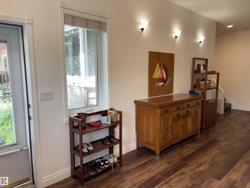 Foyer featuring a frosted glass entry door, wood-finish flooring, and white wall sconces - 14016 85 Avenue, Edmonton, AB 