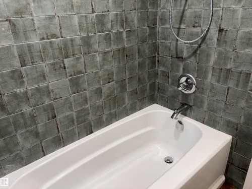 White bathtub with chrome fixtures and square-patterned wall tiling - 14016 85 Avenue, Edmonton, AB 