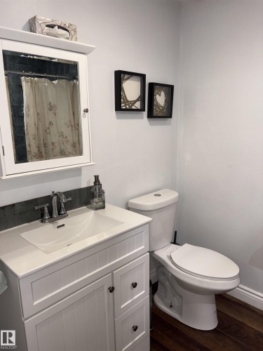 White shaker-style vanity with integrated sink, chrome faucet, and coordinating medicine cabinet - 14016 85 Avenue, Edmonton, AB 