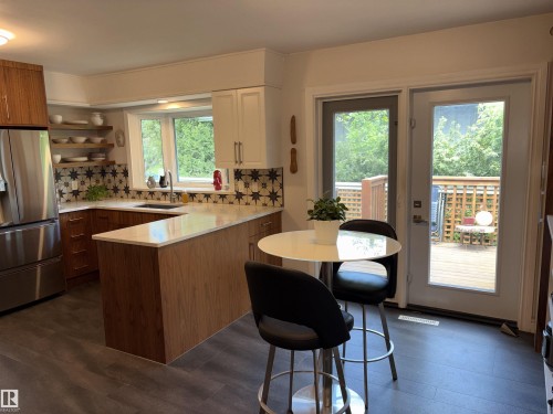 Contemporary kitchen featuring a bay window, two-tone cabinetry, patterned tile backsplash, and light countertops - 14016 85 Avenue, Edmonton, AB 
