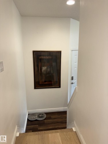 Split-level entry featuring wood-finish flooring, white baseboards, and overhead recessed lighting - 14016 85 Avenue, Edmonton, AB 