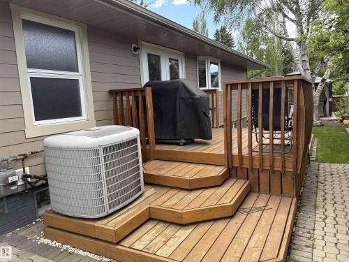 Multi-level wood deck with integrated steps, natural wood railings, and direct access to the interior via double glass doors - 14016 85 Avenue, Edmonton, AB 