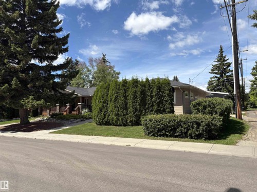 Ranch-style exterior with beige siding, a dark roof, and a covered front porch featuring stone accents - 14016 85 Avenue, Edmonton, AB 