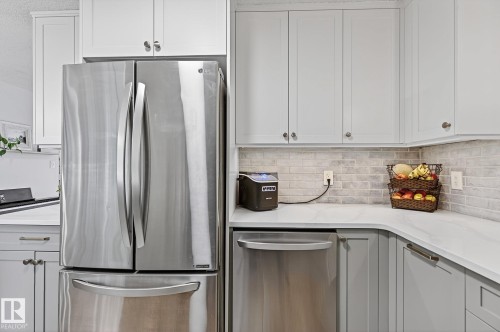 Newer stainless steel French door LG refrigerator, quartz countertops, brick backsplash, countertop lighting. - 9 Millgrove Drive, Spruce Grove, AB 