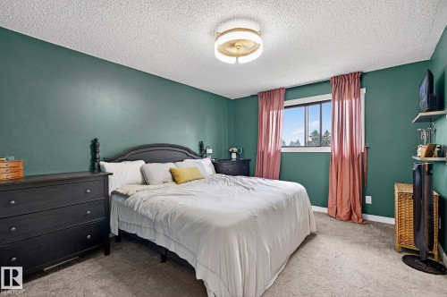 Carpeted room with a central ceiling light fixture and a window featuring a white frame - 9 Millgrove Drive, Spruce Grove, AB 