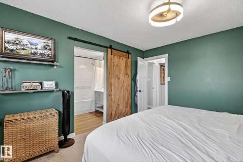 Interior space featuring a barn door entry to a bathroom, a built-in shelf system, and a modern ceiling light fixture - 9 Millgrove Drive, Spruce Grove, AB 