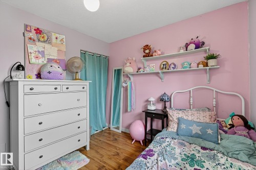 Room featuring wood-finish flooring, a white metal bed frame, and built-in wall shelving - 9 Millgrove Drive, Spruce Grove, AB 