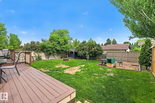 Expansive backyard featuring a pressure treated deck with railings, a manicured lawn, perimeter fencing, and mature trees - 9 Millgrove Drive, Spruce Grove, AB 