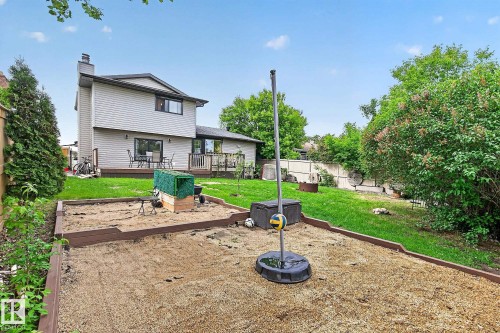 Spacious backyard featuring a sandpit area, a manicured lawn, and mature perimeter trees - 9 Millgrove Drive, Spruce Grove, AB 