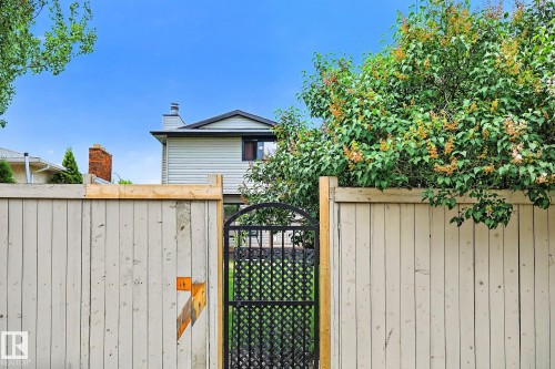 Wood-panel fencing with a black metal arched gate - 9 Millgrove Drive, Spruce Grove, AB 