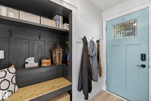 Entryway featuring a light blue door with a transom window, wall-mounted coat hooks, and light wood-finish flooring - 9 Millgrove Drive, Spruce Grove, AB 