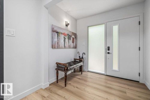 Bright entryway featuring a contemporary front door with a frosted glass sidelight and matching vertical window panel - 7 Glacier Place, St. Albert, AB 