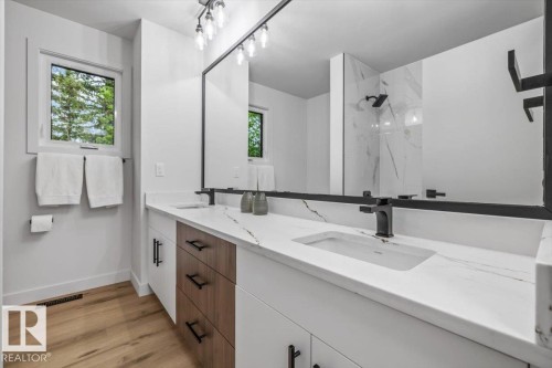 Double vanity with white cabinetry, wood-finish drawers, and white countertops featuring subtle veining - 7 Glacier Place, St. Albert, AB 