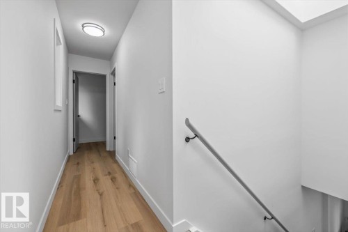Hallway featuring wood-finish flooring, white walls, and a contemporary ceiling light fixture - 7 Glacier Place, St. Albert, AB 