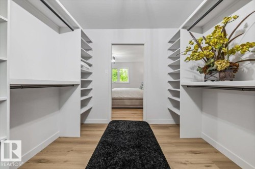 Walk-in closet featuring built-in shelving, hanging rods, light wood-finish flooring, and white baseboards - 7 Glacier Place, St. Albert, AB 