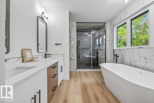 Contemporary bathroom featuring wood-finish flooring and a freestanding soaking tub - 7 Glacier Place, St. Albert, AB 
