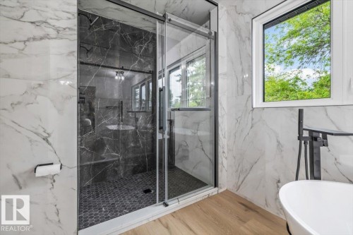 Modern bathroom featuring a glass-enclosed shower with dark marble-look tile, hex tile flooring, and matte black fixtures - 7 Glacier Place, St. Albert, AB 