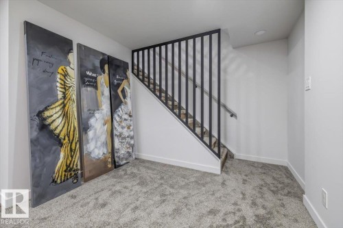 Interior staircase featuring a contemporary metal railing, light gray carpet, and white baseboards - 7 Glacier Place, St. Albert, AB 