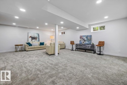 Expansive carpeted area featuring recessed lighting, a neutral color palette, and natural light from horizontal windows - 7 Glacier Place, St. Albert, AB 