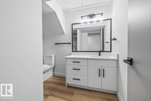 Bathroom featuring a modern white vanity with a quartz-finish countertop and black fixtures - 7 Glacier Place, St. Albert, AB 