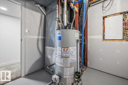 Water heater installation with exposed utility lines and a visible electrical panel - 7 Glacier Place, St. Albert, AB 