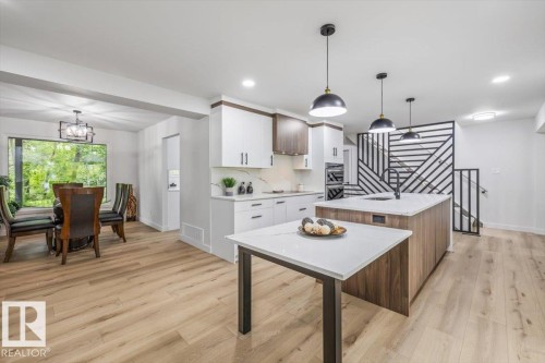 Contemporary kitchen featuring a large island with a black faucet, white countertops, two-tone cabinetry, and pendant lighting - 7 Glacier Place, St. Albert, AB 