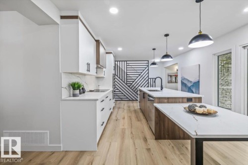 Modern kitchen featuring white cabinetry, light wood-finish flooring, and white countertops with veining - 7 Glacier Place, St. Albert, AB 