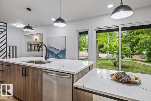 Kitchen featuring a large central island with a built-in sink and stainless steel dishwasher - 7 Glacier Place, St. Albert, AB 