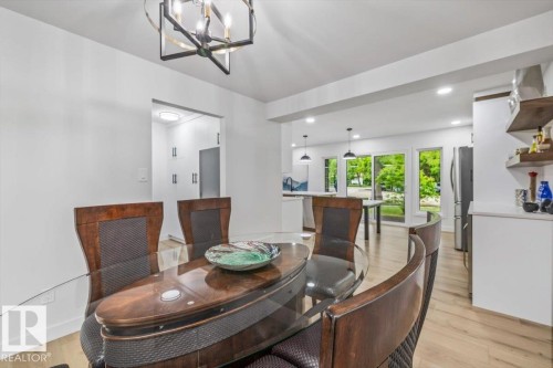 Open-concept dining area featuring wood-finish flooring and a contemporary chandelier - 7 Glacier Place, St. Albert, AB 