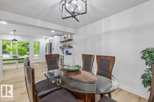 Open-concept dining area featuring light wood-finish flooring, a contemporary chandelier, and recessed lighting - 7 Glacier Place, St. Albert, AB 