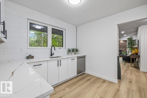 Kitchen featuring white cabinetry with matte black hardware, a stainless steel dishwasher, and a black faucet at the sink - 7 Glacier Place, St. Albert, AB 