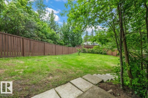 Expansive backyard featuring a manicured lawn, a full-height privacy fence, mature perimeter trees, and concrete paver steps - 7 Glacier Place, St. Albert, AB 