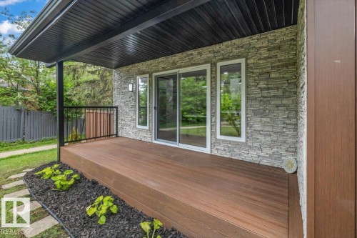 Expansive wood-finish deck featuring a black metal railing and overhead soffit - 7 Glacier Place, St. Albert, AB 