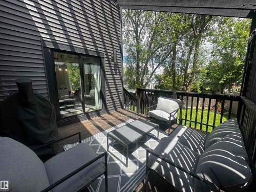 Spacious outdoor deck with dark wood-finish flooring, black railing, and direct access to interior via sliding glass doors - 38 Woodcrest Avenue, St. Albert, AB 