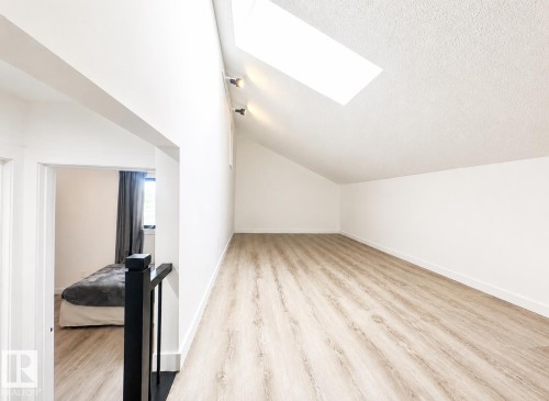 Spacious attic area featuring wood-finish flooring, a skylight, and white walls - 38 Woodcrest Avenue, St. Albert, AB 