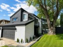 Modern exterior featuring white painted brick, dark vertical siding, a two-car garage, and a sloped lawn with mature tree - 38 Woodcrest Avenue, St. Albert, AB 
