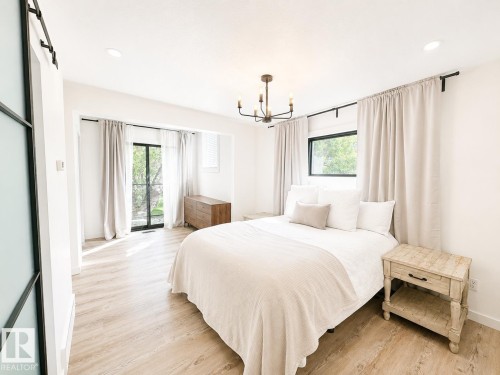 Room featuring light wood-finish flooring, a contemporary black chandelier, recessed lighting, and a sliding glass door with transom window - 38 Woodcrest Avenue, St. Albert, AB 