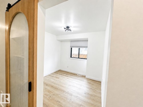 Room featuring wood-finish flooring, a contemporary ceiling light fixture, and a window with a roller shade - 38 Woodcrest Avenue, St. Albert, AB 