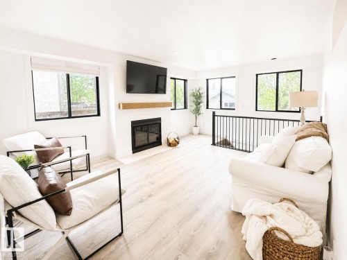 Living area featuring light wood-finish flooring and multiple black-framed windows - 38 Woodcrest Avenue, St. Albert, AB 