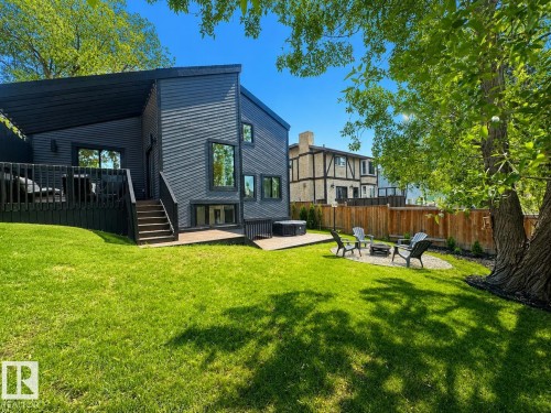 Modern exterior featuring dark horizontal siding, a spacious deck with dark railing, and a ground-level patio - 38 Woodcrest Avenue, St. Albert, AB 