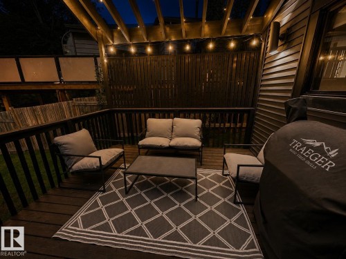 Wood-finish deck featuring a slatted privacy screen, overhead pergola, and string lighting - 38 Woodcrest Avenue, St. Albert, AB 