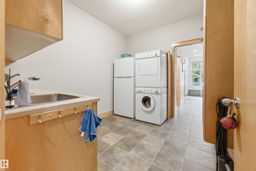 Utility room featuring light wood-finish cabinetry, a stainless steel undermount sink with a chrome faucet, and checkerboard floor tiling - A38 Bernice Ave, Rural Leduc County, AB 