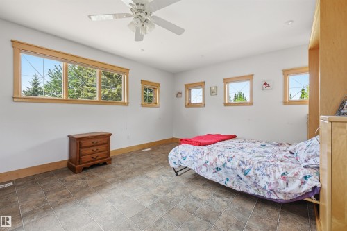 Spacious room featuring multiple windows with wood trim, a ceiling fan, and durable tile flooring - A38 Bernice Ave, Rural Leduc County, AB 