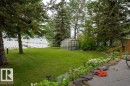 Expansive green lawn with mature trees and a clear-paneled greenhouse - A38 Bernice Ave, Rural Leduc County, AB 