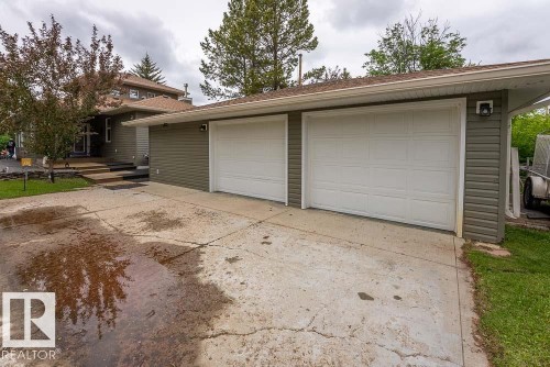 Attached two-car garage with white paneled doors and an exterior light fixture - A38 Bernice Ave, Rural Leduc County, AB 