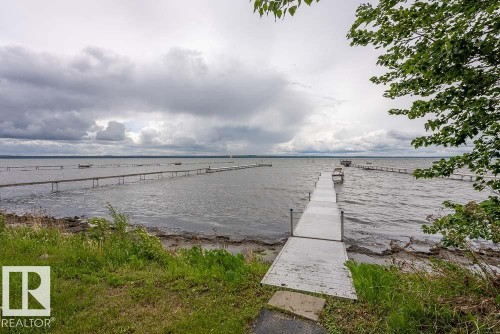 Waterfront property featuring a private dock extending into the water, expansive water frontage, and mature trees providing natural privacy - A38 Bernice Ave, Rural Leduc County, AB 