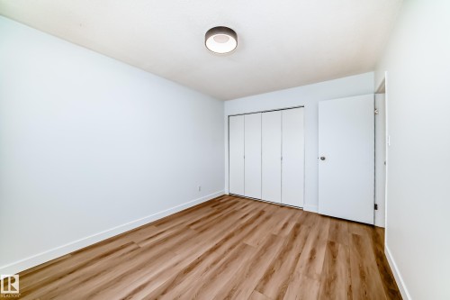Bright interior space featuring wood-finish flooring, white baseboards, and a contemporary flush-mount ceiling light - 9D Castle Terrace, Edmonton, AB 