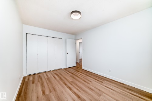 Room featuring wood-finish flooring, white walls, and a modern ceiling light fixture - 9D Castle Terrace, Edmonton, AB 