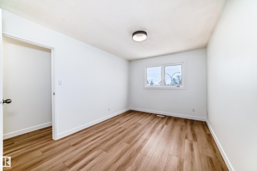 Bright interior room with wood-finish flooring, white baseboards, and a contemporary ceiling fixture - 9D Castle Terrace, Edmonton, AB 