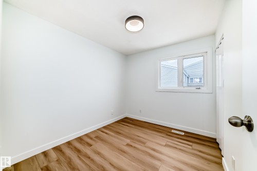 Room featuring wood-finish flooring, white walls, and a modern ceiling light fixture - 9D Castle Terrace, Edmonton, AB 